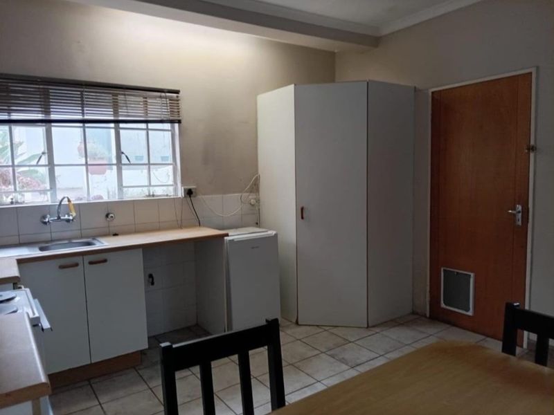 A functional kitchen featuring tiled flooring, built-in cabinetry, a laminate countertop, and a sink with a window view.
