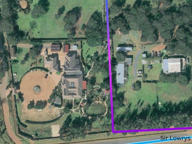 Aerial view of a large farm property featuring a main residence with solar panels, extensive gardens, and multiple outbuildings on a spacious plot.