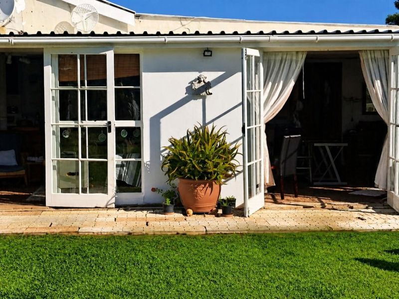 Rear view of the farmhouse featuring a paved patio area accessible through double french doors, with an integrated air conditioning unit.
