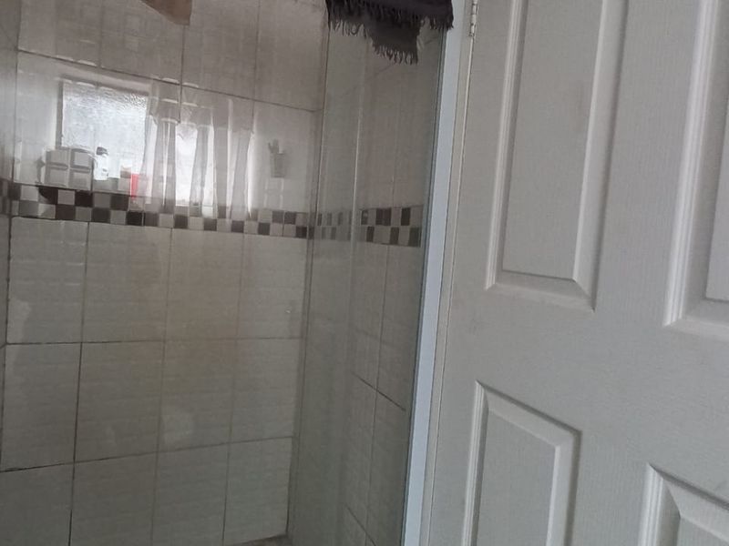 A functional bathroom shower enclosure featuring tiled walls and a standard panel door.
