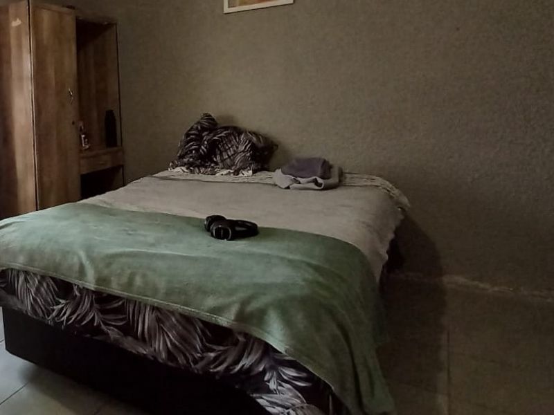 A bedroom featuring tiled flooring and textured wall finishes, requiring cosmetic updates to improve the overall aesthetic and appeal.