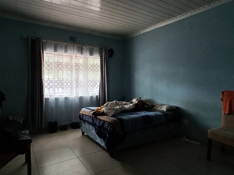 A bedroom featuring tiled flooring, a timber ceiling, and a window fitted with a security gate.