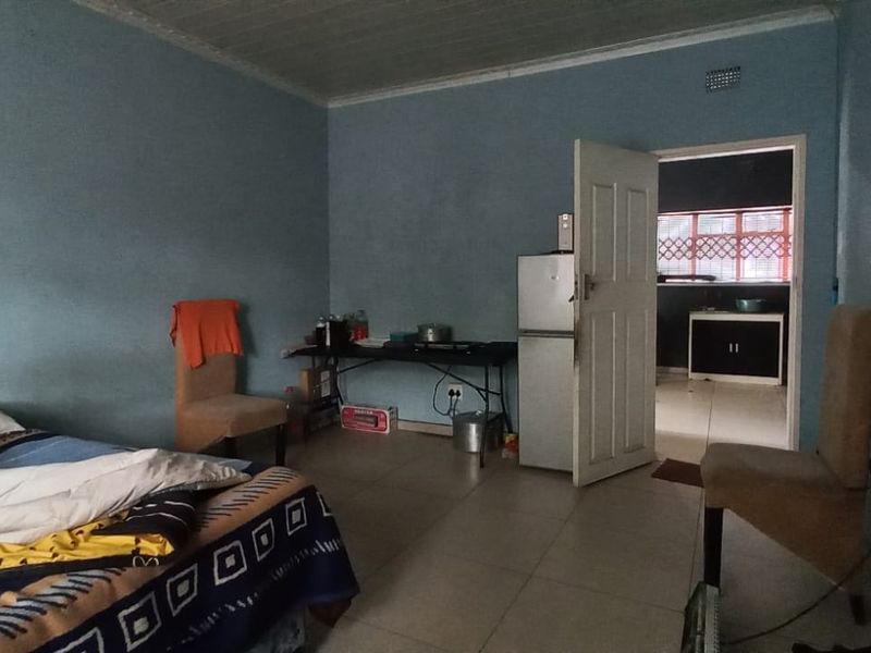 A bedroom featuring tiled flooring and direct access to an adjacent room, requiring cosmetic updates to improve the overall finish and appeal.