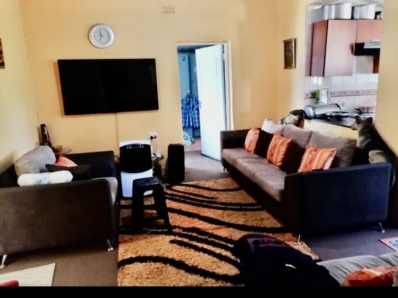 Open plan living area featuring a connected kitchen space with built-in cabinetry and an extractor fan.