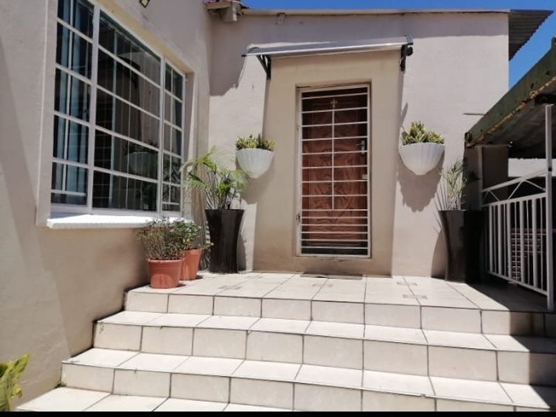 Front entrance featuring tiled steps, a security gate, and window bars, providing a functional and secure access point to the home.