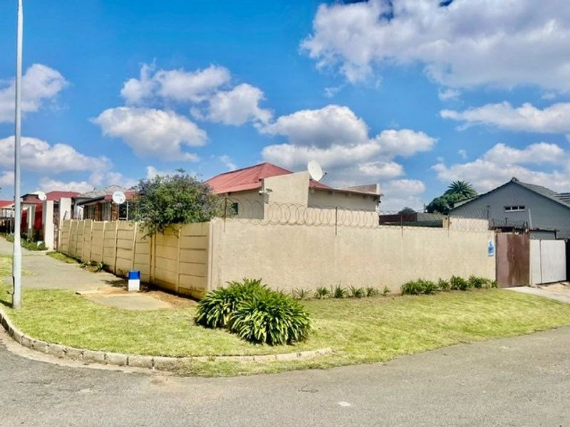 Street view of the property showing the perimeter boundary wall with security razor wire and access gate.