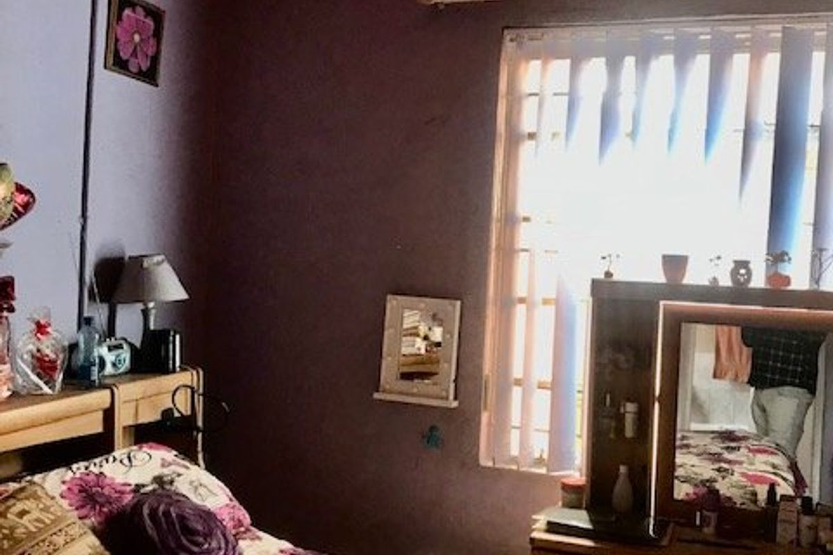 A bedroom featuring a timber tongue and groove ceiling and vertical blinds, currently requiring cosmetic updates to the wall finishes and electrical presentation.