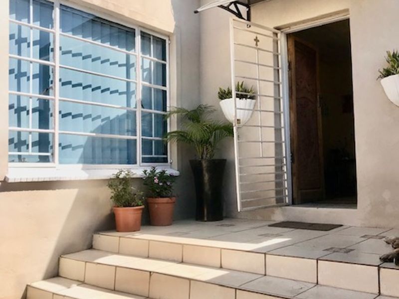 Entrance area featuring a tiled staircase leading to a secure doorway with a metal security gate and large window.