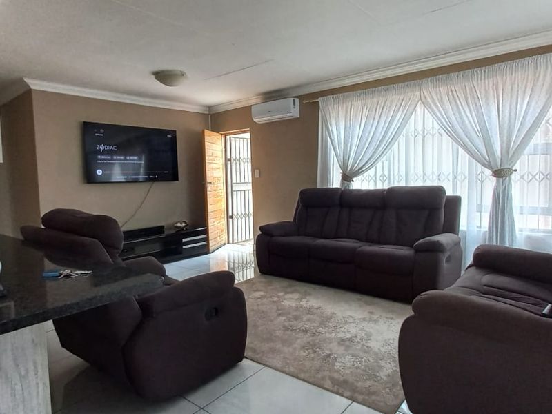 Open-plan living area featuring tiled floors, a split-system air conditioner, and a modern kitchen with granite countertops.