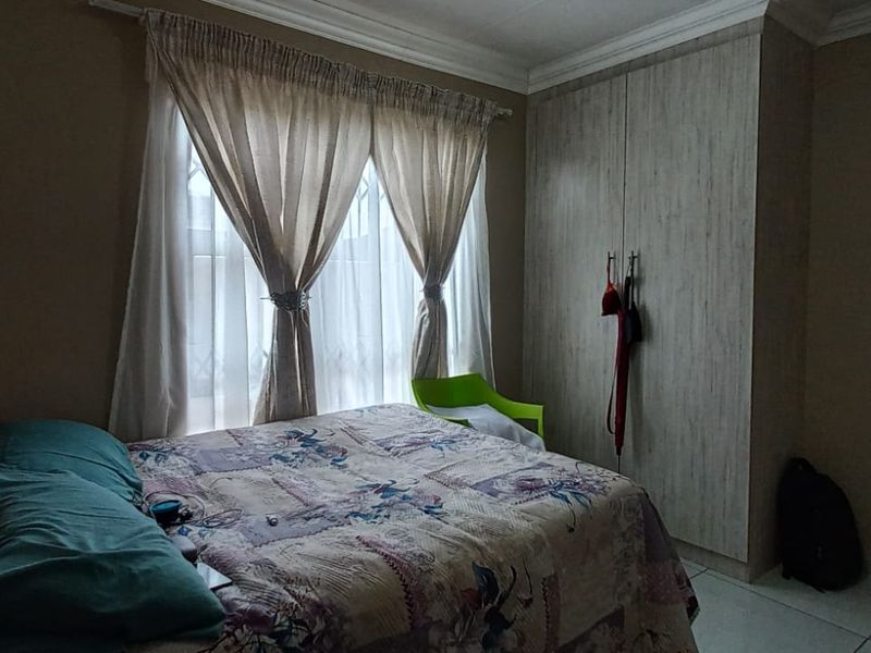 A bedroom featuring built-in cupboards, tiled flooring, and decorative cornice detailing.