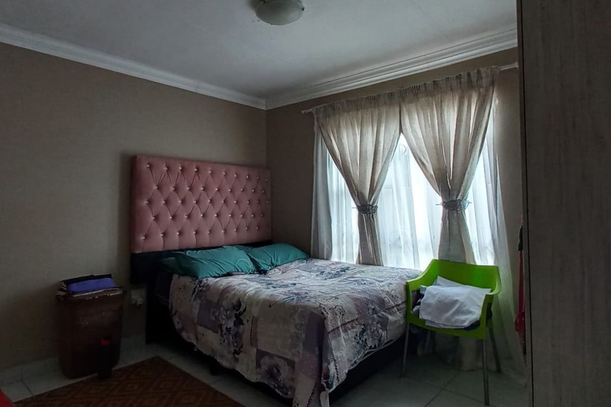 A bedroom featuring tiled flooring and decorative cove cornicing, providing a functional space with natural light from the window.