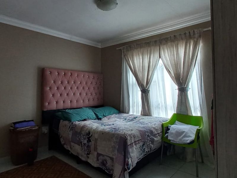 A bedroom featuring tiled flooring and decorative cove cornicing, providing a functional space with natural light from the window.