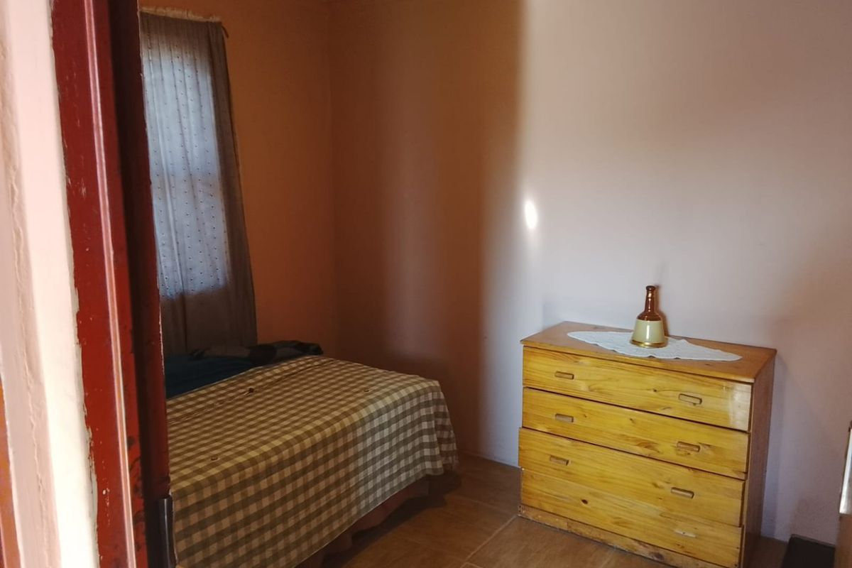 A compact bedroom featuring tiled flooring and a window, currently requiring cosmetic updates to improve its overall appeal and condition.