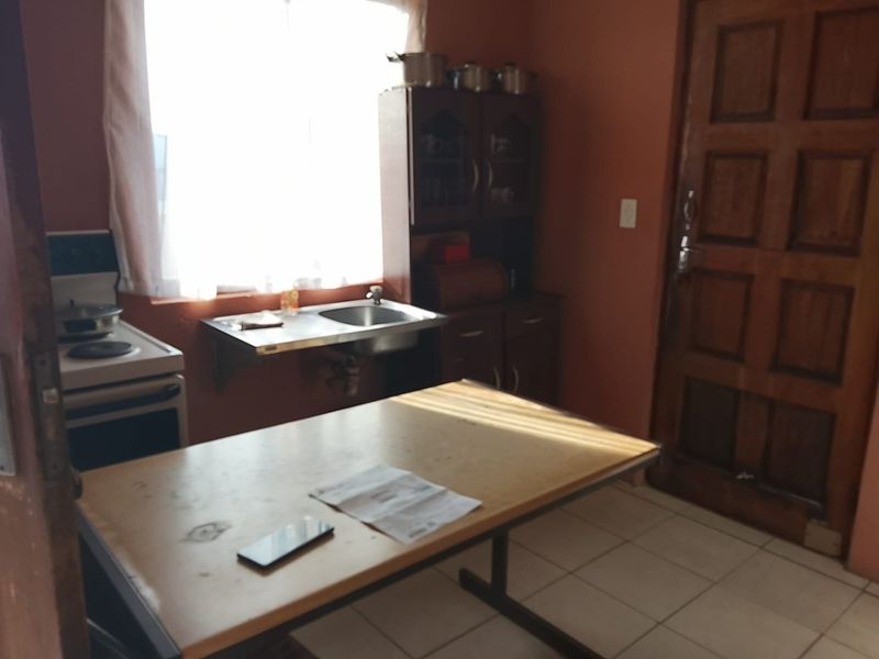 A compact kitchen area featuring tiled flooring, built-in cabinetry, and a stainless steel sink, offering a functional space with potential for modernization.