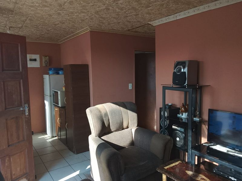 A living area featuring tiled flooring and a textured ceiling with coving, currently used as a multi-purpose space.