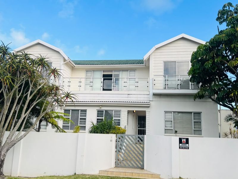 A well-maintained double-story residential property featuring a white facade, upper-level balcony with glass balustrades, and a secure gated entrance.