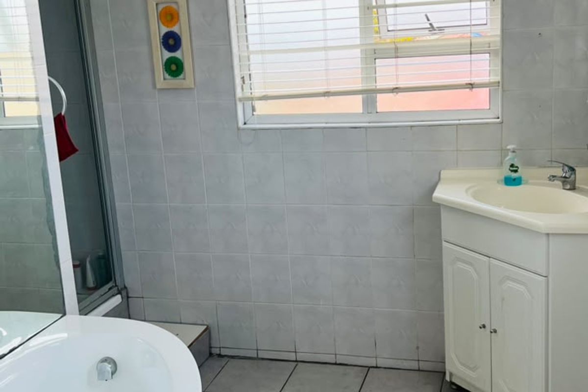 A functional bathroom featuring a corner bathtub, separate shower enclosure, vanity cabinet with basin, and tiled finishes throughout.