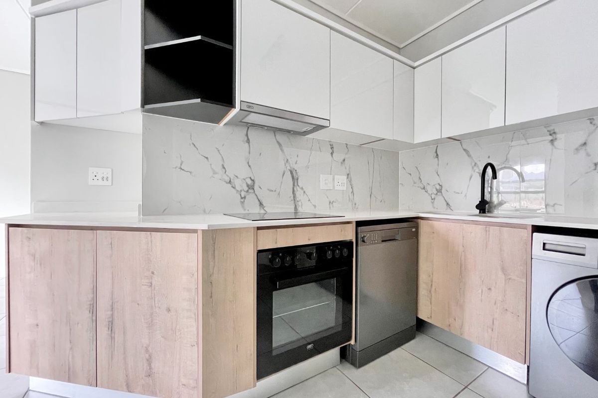 Modern kitchen featuring sleek white and wood-grain cabinetry, marble-look splashbacks, integrated oven, electric hob, and high-quality finishes throughout.