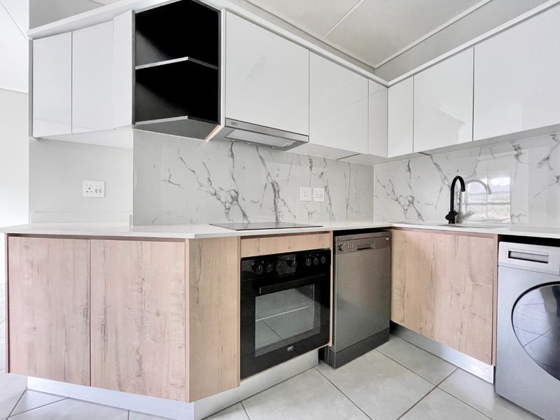 Modern kitchen featuring sleek white and wood-grain cabinetry, marble-look splashbacks, integrated oven, electric hob, and high-quality finishes throughout.
