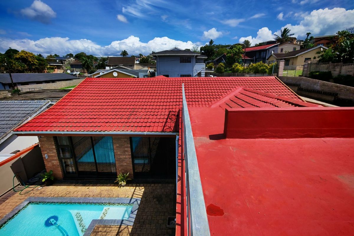 Aerial view of the property showing a combination of tiled and flat roofing, a swimming pool, and paved outdoor area.