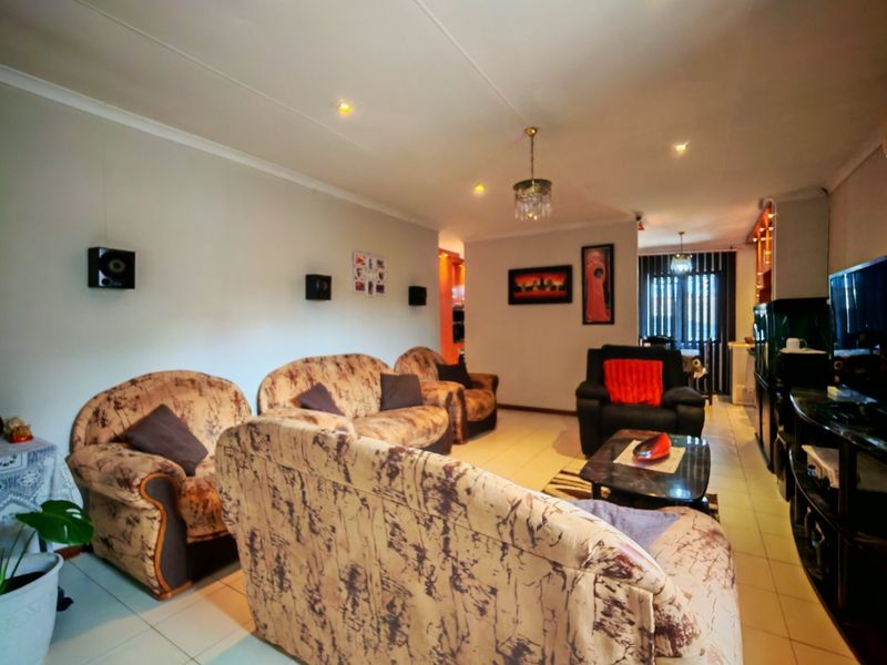 A spacious living room featuring neutral tiled flooring, coved ceilings with recessed lighting, and a functional layout suitable for comfortable family living.
