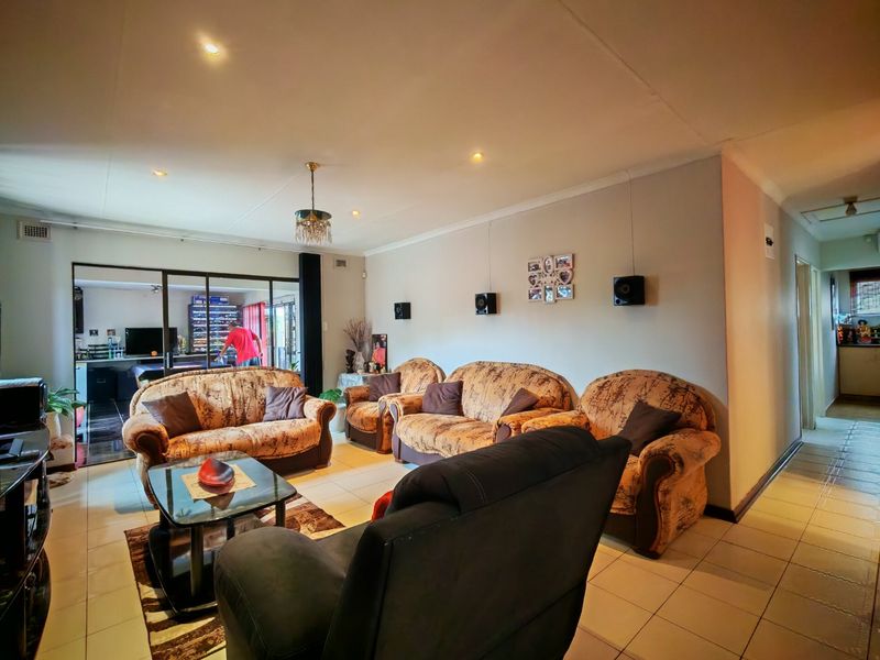 Spacious living room featuring tiled flooring, recessed downlighting, and sliding glass doors leading to an adjacent area.