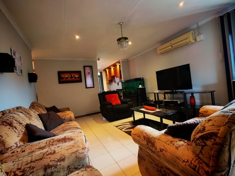 Open-plan living area featuring tiled flooring, recessed lighting, and a wall-mounted air conditioning unit, providing a functional and connected space.