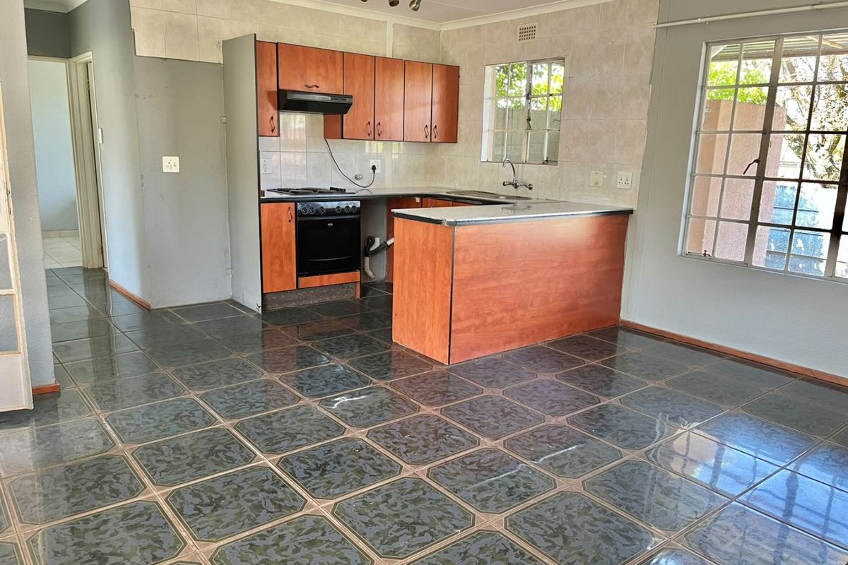 A functional kitchen featuring laminate cabinetry, built-in oven, hob, and tiled flooring. The space is vacant and ready for renovation or cosmetic updates.