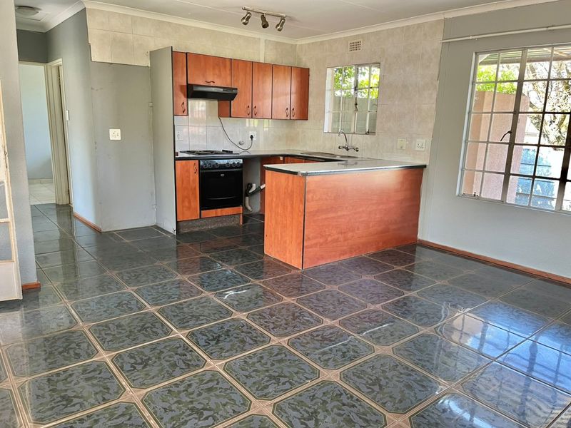 A functional kitchen featuring laminate cabinetry, built-in oven, hob, and tiled flooring. The space is vacant and ready for renovation or cosmetic updates.