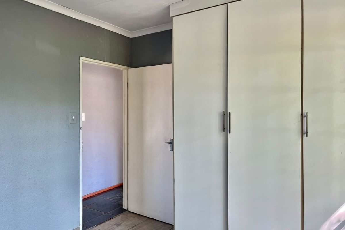A bedroom featuring built-in cupboards and laminate flooring, providing a neutral base for personalization.