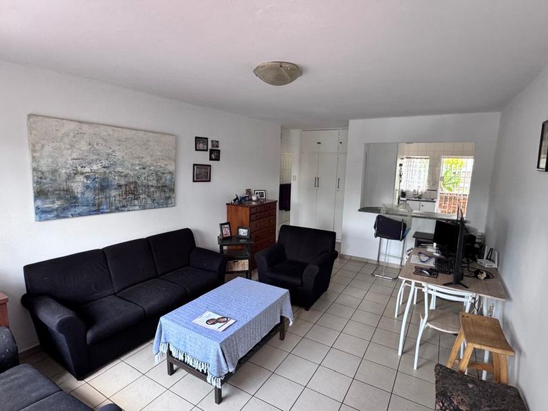 Open-plan living area featuring tiled flooring, built-in storage cupboards, and a breakfast bar connecting to the kitchen space.