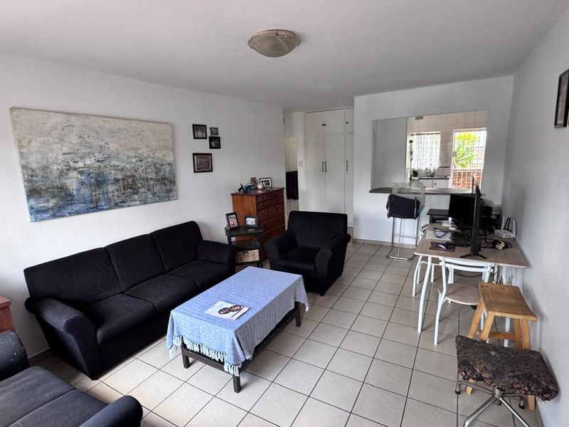 Open-plan living area featuring tiled flooring, built-in storage cupboards, and a breakfast bar connecting to the kitchen space.