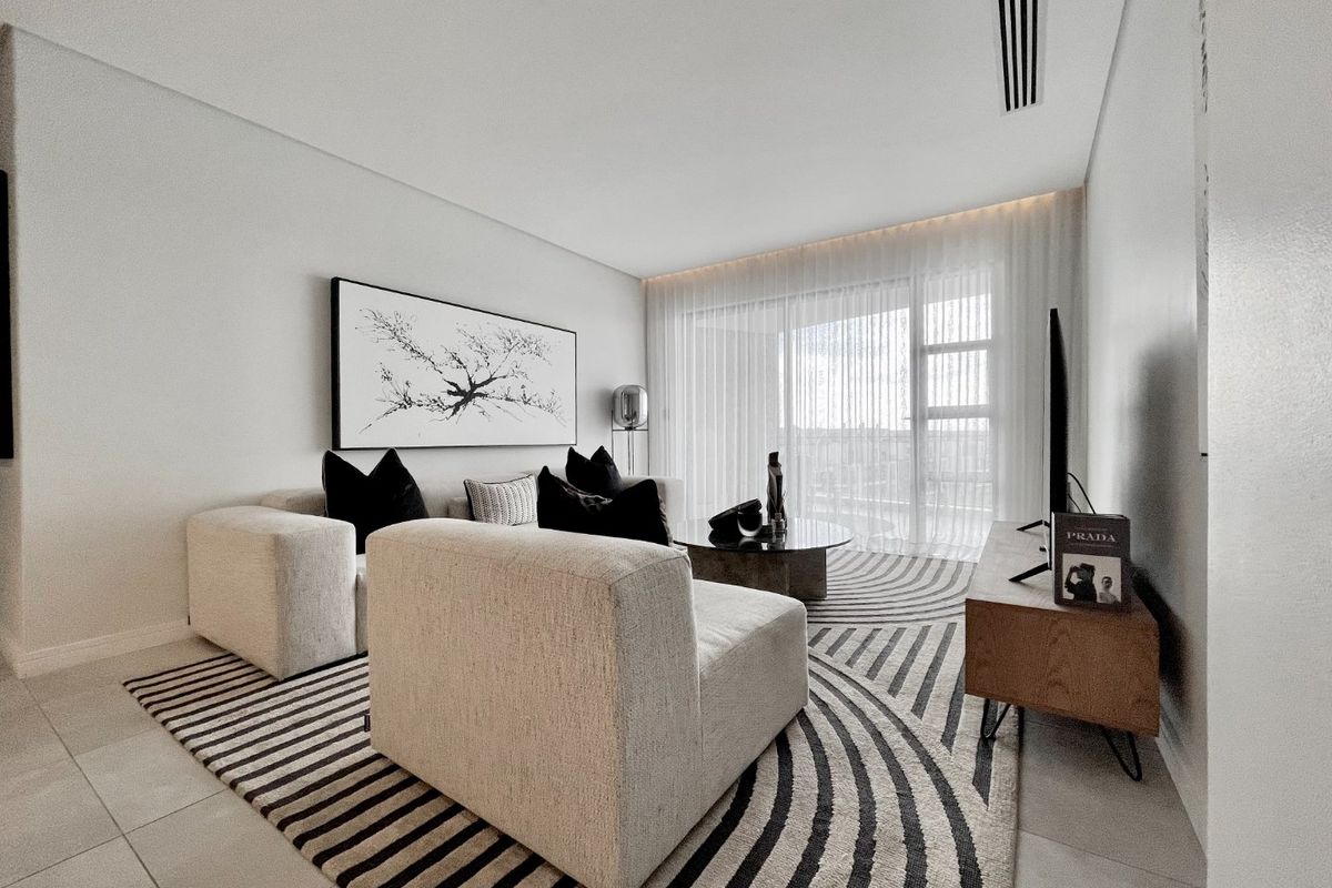 Modern living room featuring neutral tiled flooring, recessed ceiling lighting, and a large sliding glass door providing access to the balcony.