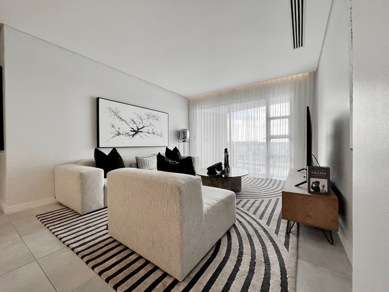Modern living room featuring neutral tiled flooring, recessed ceiling lighting, and a large sliding glass door providing access to the balcony.