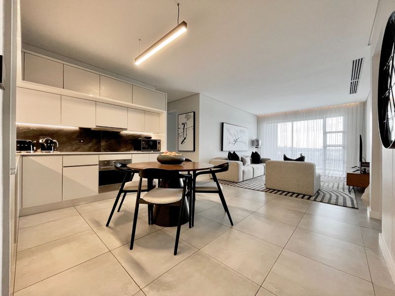 Modern open-plan living area featuring a sleek kitchen with integrated appliances, high-quality floor tiles, and seamless flow to a bright, light-filled lounge space.