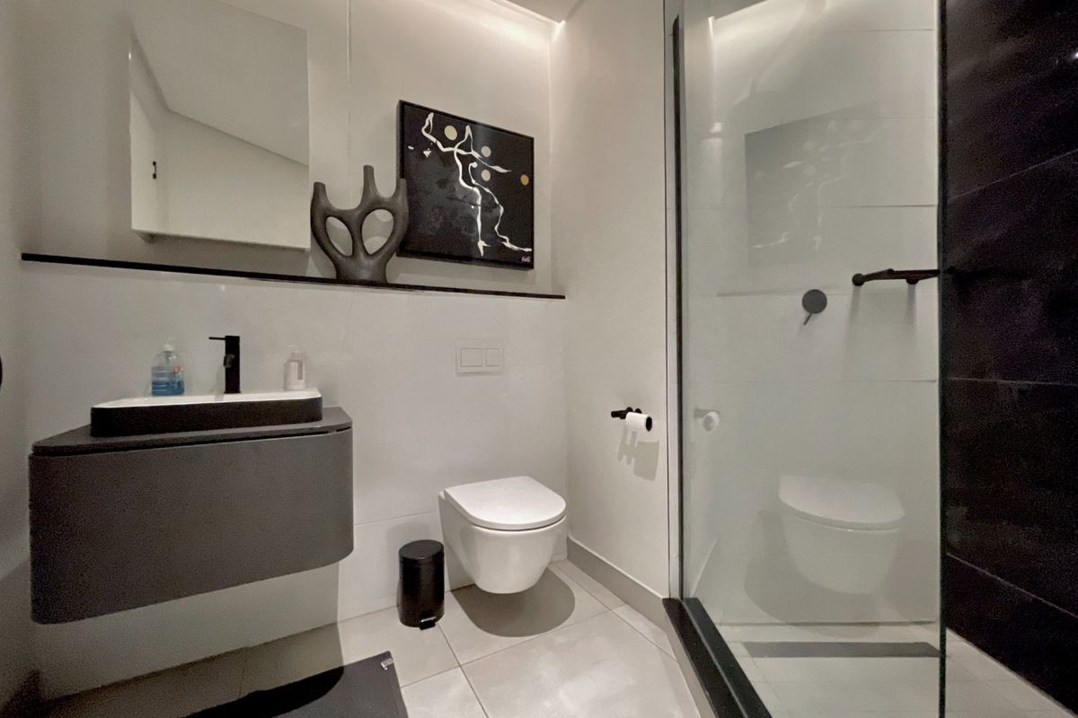 Modern bathroom featuring a wall-mounted vanity, vessel sink, wall-hung toilet, and a sleek glass-enclosed shower with contemporary finishes.