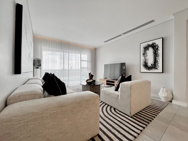 A modern, well-maintained living room featuring tiled floors, ducted air conditioning, and large sliding glass doors that provide ample natural light.