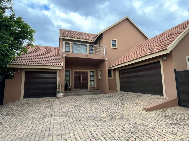 A well-maintained double-story residence featuring a paved driveway, double garage, and a prominent front entrance with an upper-level balcony.