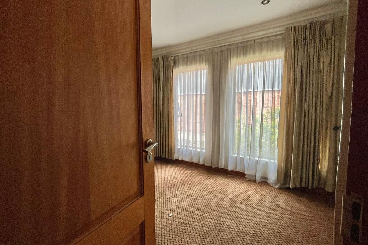 A vacant bedroom featuring carpeted flooring, recessed downlighting, and large windows with floor-to-ceiling curtains.
