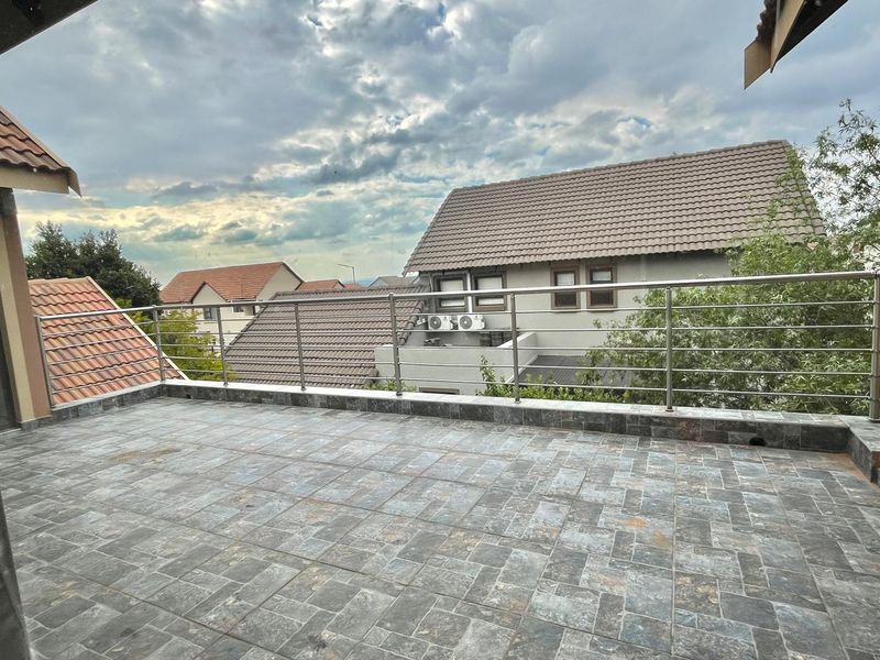 An open-air balcony featuring durable tiled flooring and a modern stainless steel balustrade, offering an elevated outdoor space with neighbourhood views.