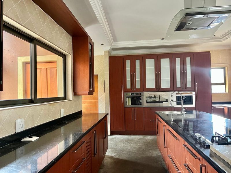 Spacious kitchen featuring dark wood cabinetry, granite countertops, a central island, and integrated appliances, awaiting final flooring installation.