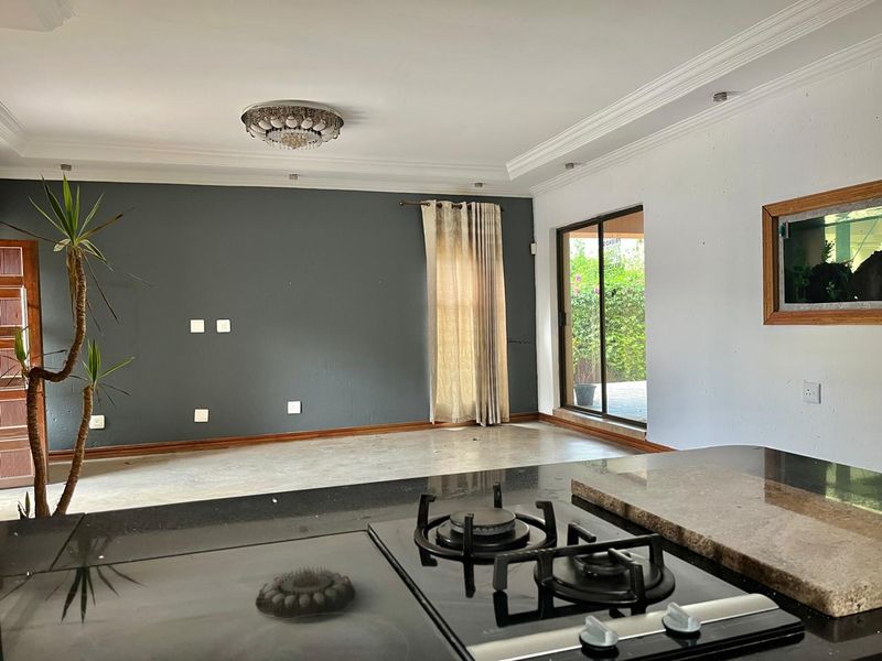 Open plan living area featuring a modern kitchen with granite countertops and gas hob, flowing into a spacious lounge with sliding door access.