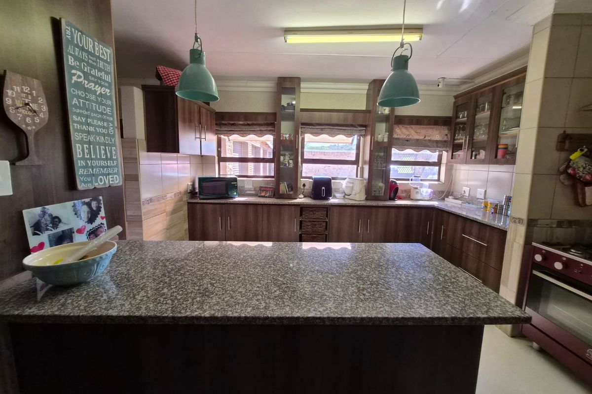 A functional kitchen featuring dark wood cabinetry, granite countertops, and a central island, providing ample workspace and storage for daily culinary activities.
