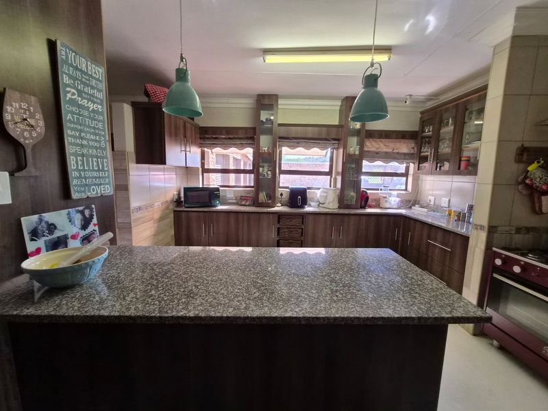 A functional kitchen featuring dark wood cabinetry, granite countertops, and a central island, providing ample workspace and storage for daily culinary activities.