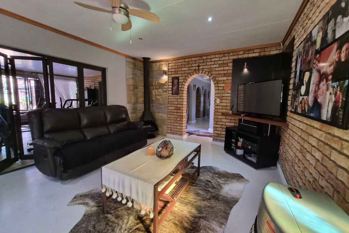 A cozy living room featuring an exposed brick wall, a characterful archway, and a freestanding fireplace, with direct access to the outdoor area.