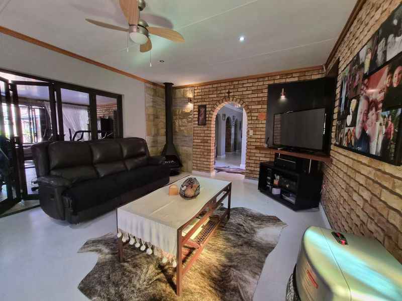 A cozy living room featuring an exposed brick wall, a characterful archway, and a freestanding fireplace, with direct access to the outdoor area.
