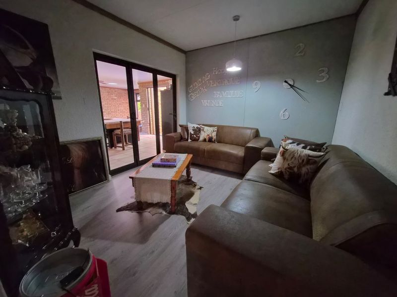 A living room featuring laminate flooring, pendant lighting, and sliding glass doors that open to an adjacent patio area.