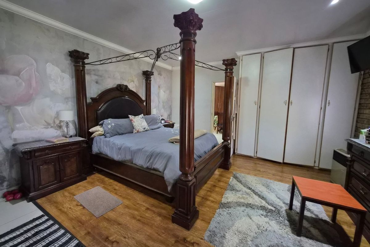 Spacious bedroom featuring laminate flooring, built-in cupboards, and recessed lighting, offering a functional layout with ample storage space.