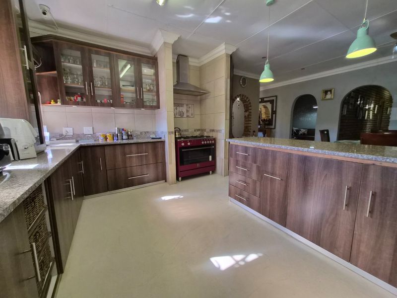Spacious kitchen featuring dark wood cabinetry, granite countertops, a central island, and a freestanding gas stove with a stainless steel extractor fan.