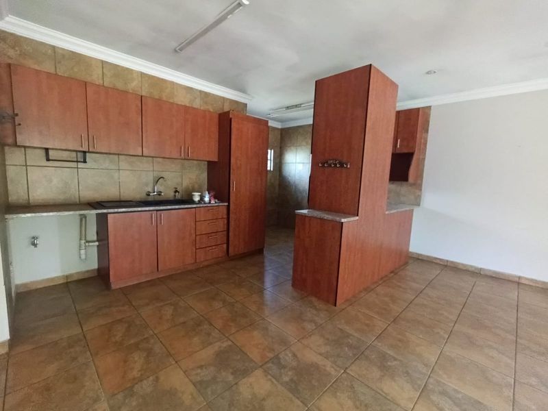 A functional kitchen featuring wood-look cabinetry, tiled flooring, and a tiled backsplash, offering a clean, empty space ready for modernization.